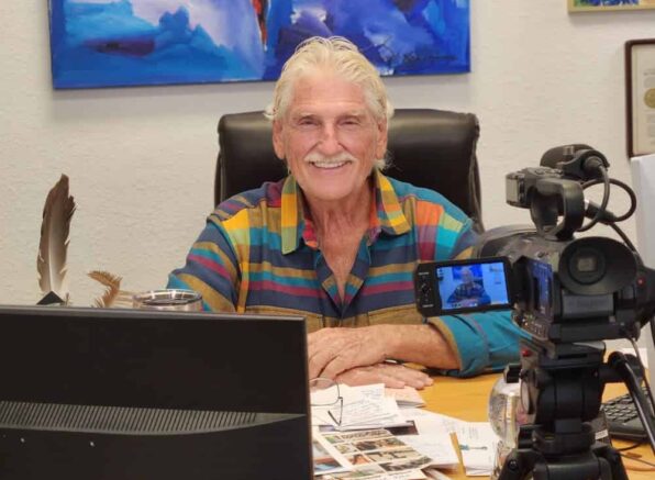 Robert Morse, N.D., D.Sc., M.H. in colorful shirt preparing for recording session with camera and microphone setup.